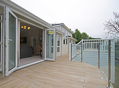 AB Sundecks Wood Effect Decking and Picket Glass surrounding a Lodge