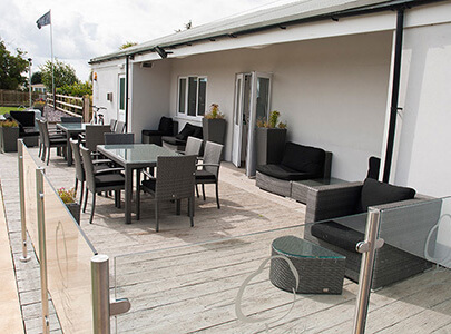 AB Sundecks Decking and Steel Glass Handrails behind building with an array of chairs and tables